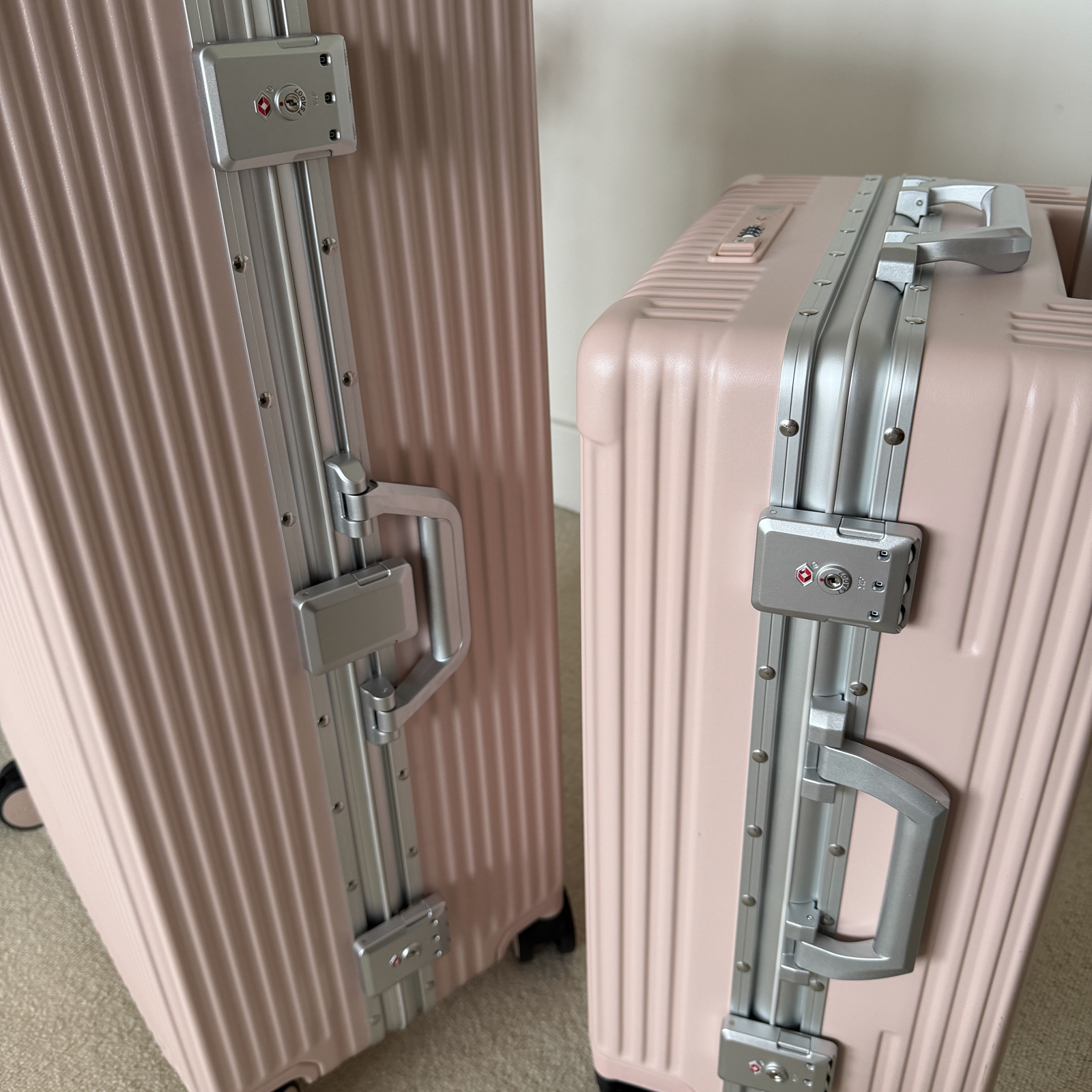 Close view of both TSA locks on a dark NOBL carry-on at the airport