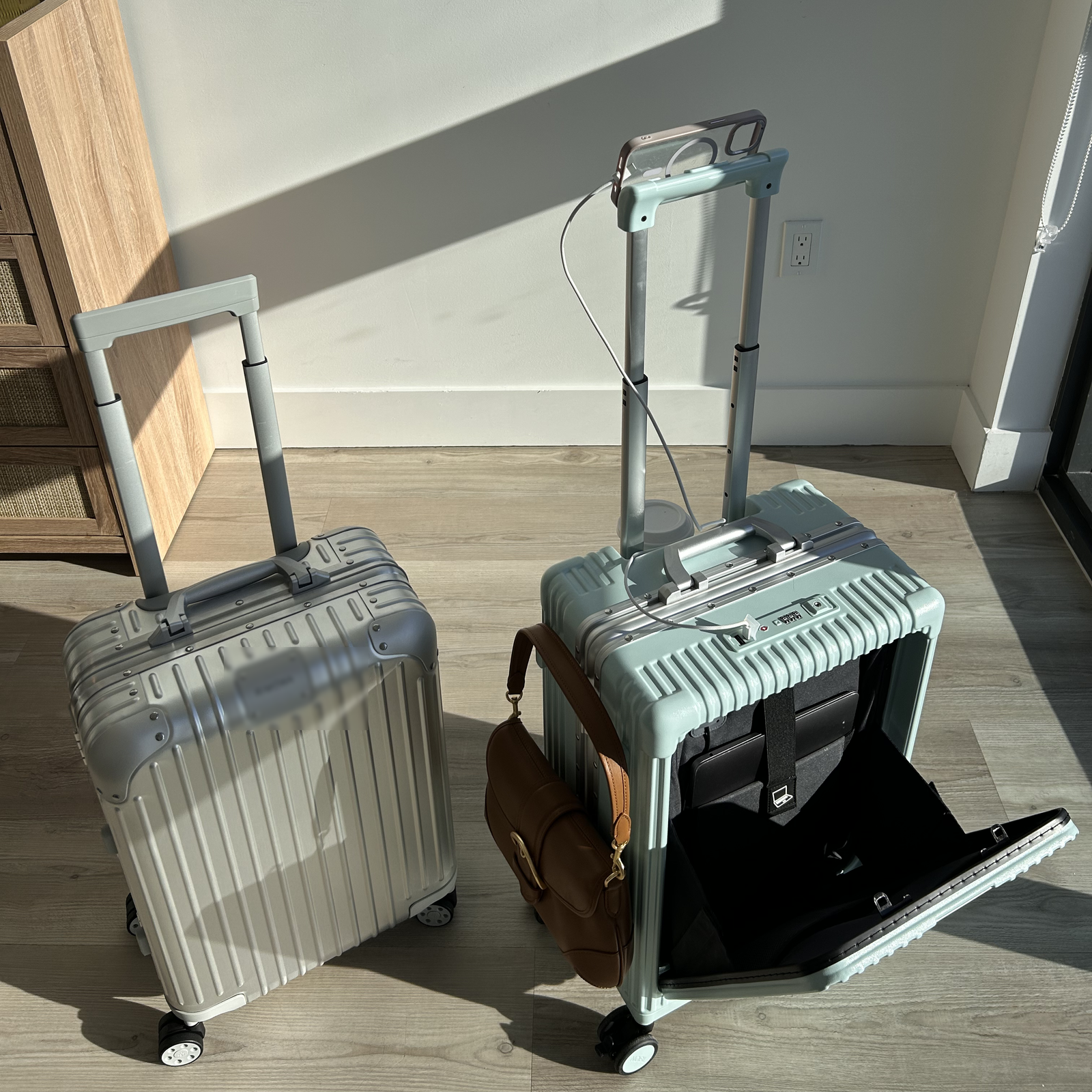 Traveler seated calmly at the airport beside a silver NOBL carry-on and NOBL billboard
