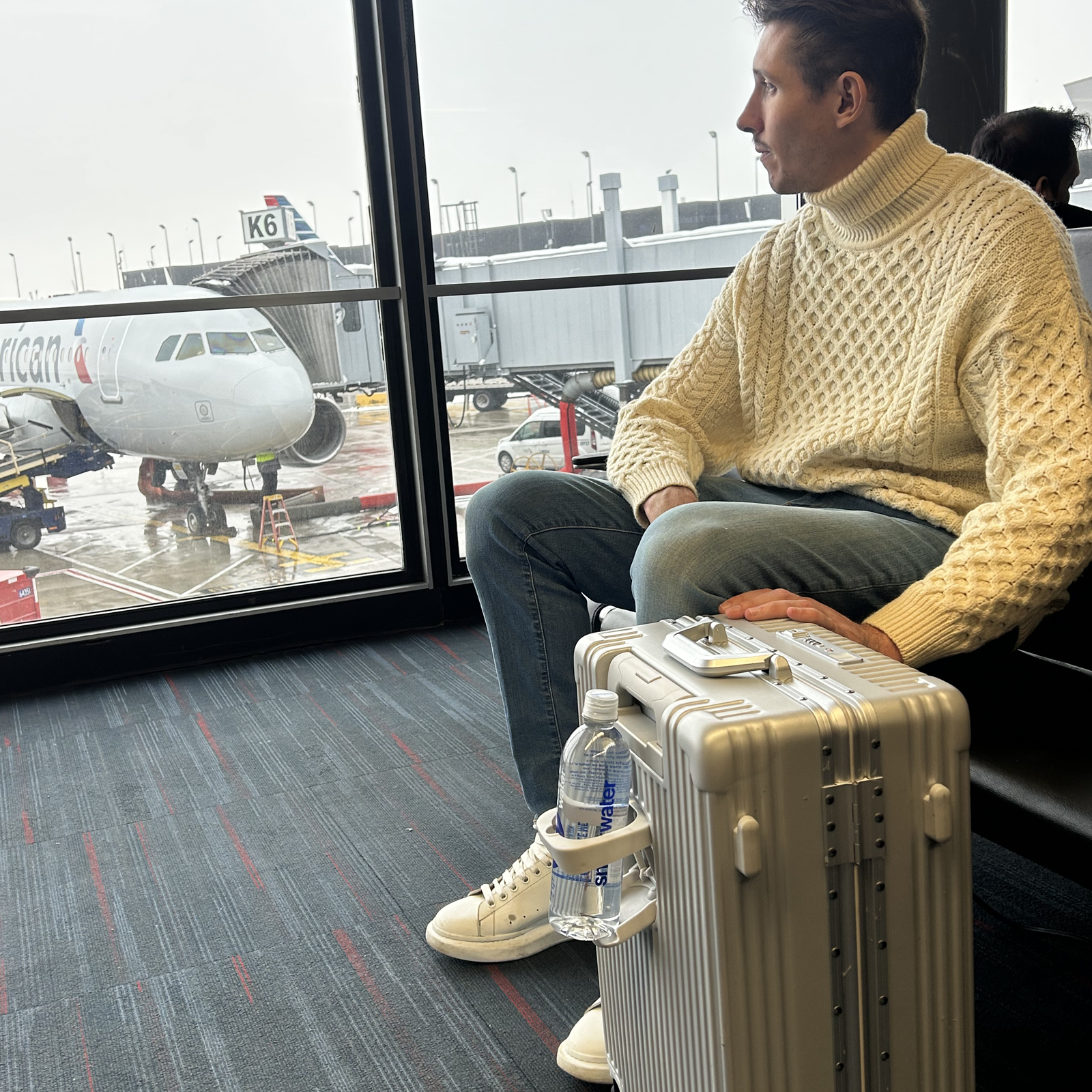 Traveler walking through the airport with a dark NOBL carry-on