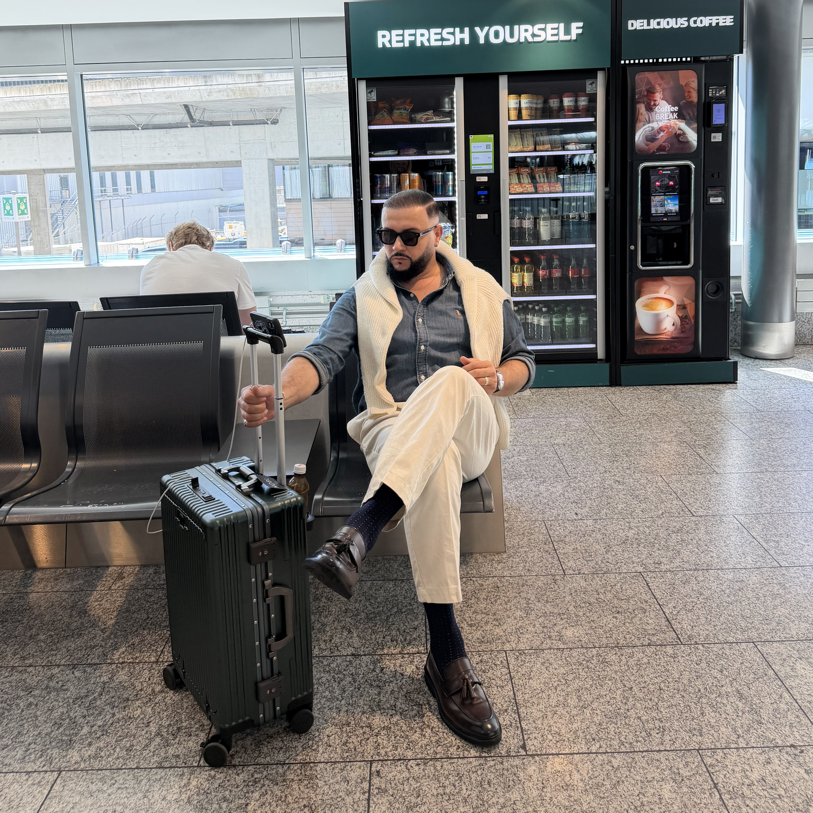 Traveler standing beside a green NOBL carry-on at the Royal Pavilion